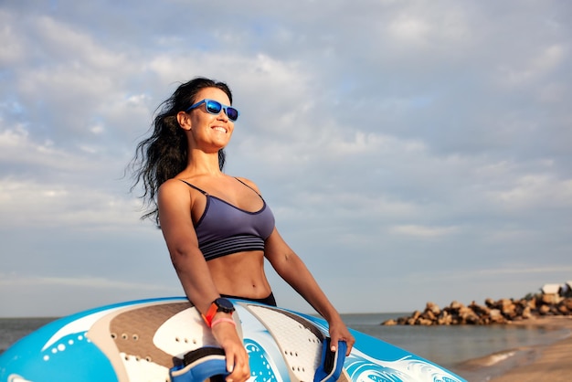 Young smiling woman with surf stands on the beach