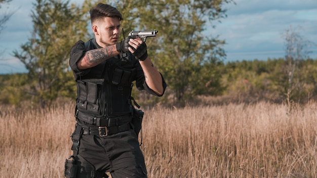 Young soldier in black uniform aiming a pistol