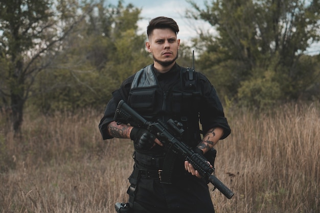 Young soldier in black uniform with an assault rifle