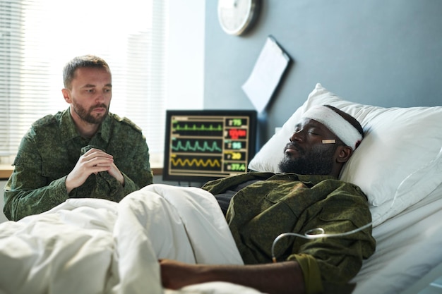 Young soldier with bandaged head lying in hospital bed