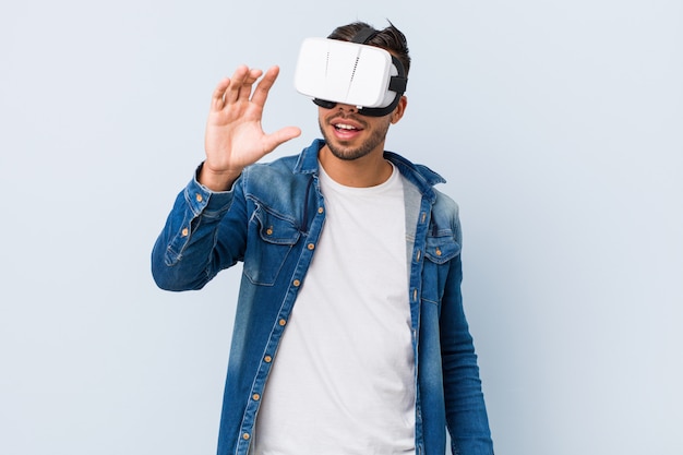 Young south-asian man playing with virtual reality glasses