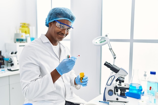 Young south east man wearing scientist uniform holding pill at laboratory