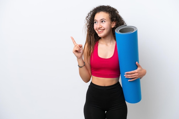 Young sport Arab woman going to yoga classes while holding a mat isolated on white background intending to realizes the solution while lifting a finger up