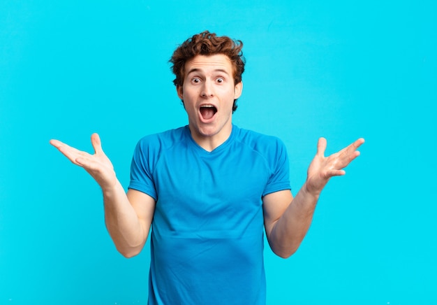 Young sport boy feeling happy, excited, surprised or shocked, smiling and astonished at something unbelievable