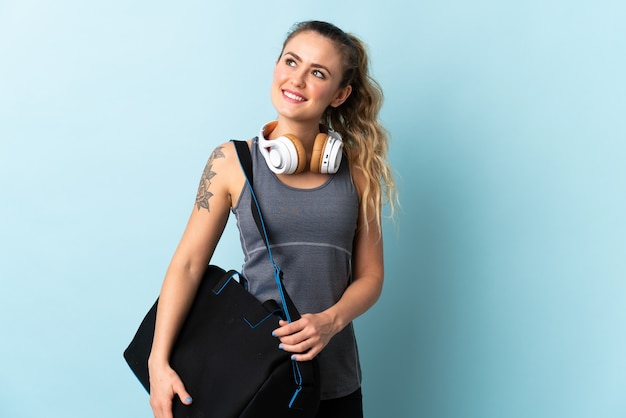 Young sport Brazilian woman with sport bag isolated on blue thinking an idea while looking up