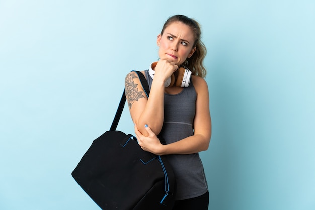 Young sport Brazilian woman with sport bag isolated  having doubts and thinking