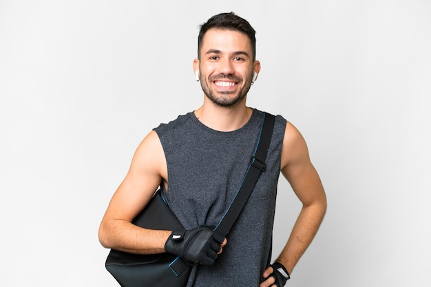 Young sport caucasian man with sport bag over over isolated white background posing with arms at hip and smiling