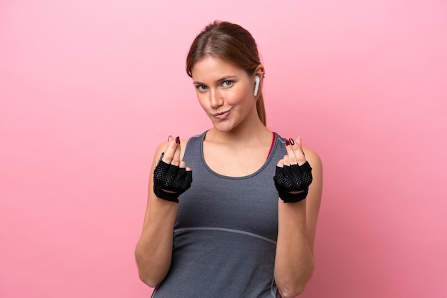 Young sport caucasian woman isolated on pink background making money gesture