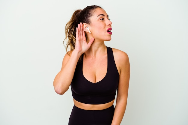 Young sport caucasian woman isolated on white trying to listening a gossip.