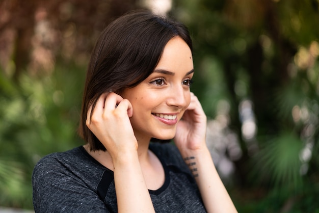 Young sport caucasian woman listening music at outdoors in a park