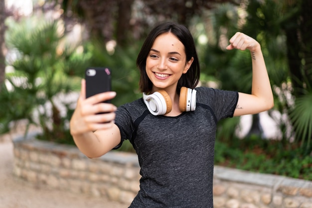 Young sport caucasian woman making a selfie at outdoors in a park