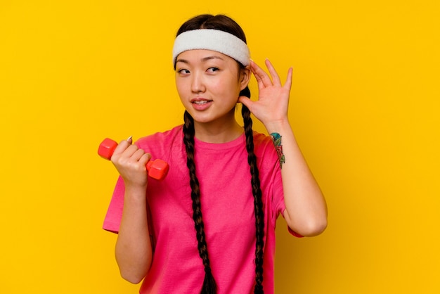 Young sport chinese woman  trying to listening a gossip.