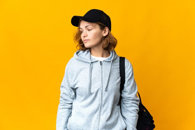 Young sport Georgian woman with sport bag over isolated wall looking to the side