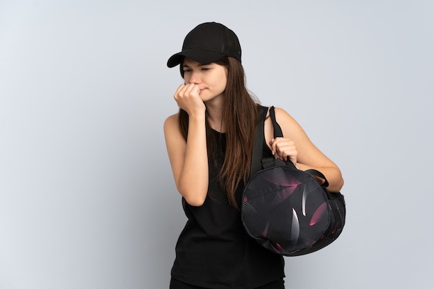 Young sport girl with sport bag isolated on grey having doubts