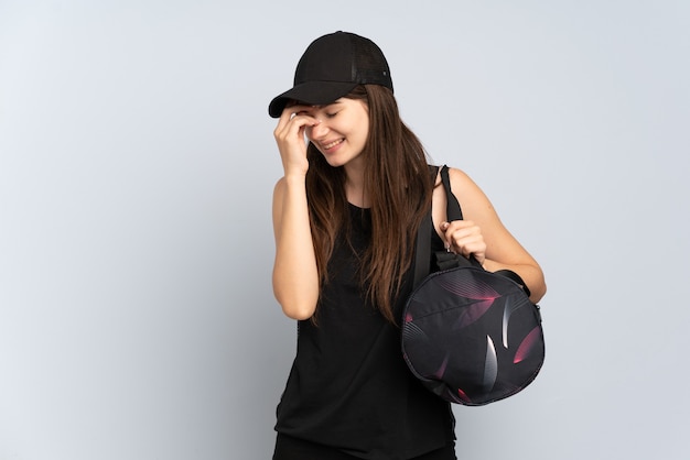 Young sport girl with sport bag isolated on grey laughing