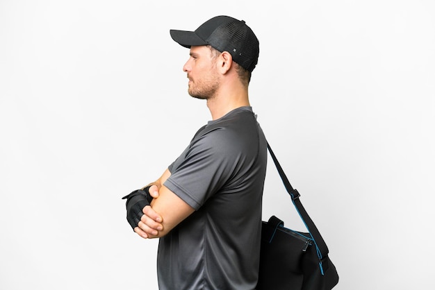 Young sport man with sport bag over isolated white background in lateral position