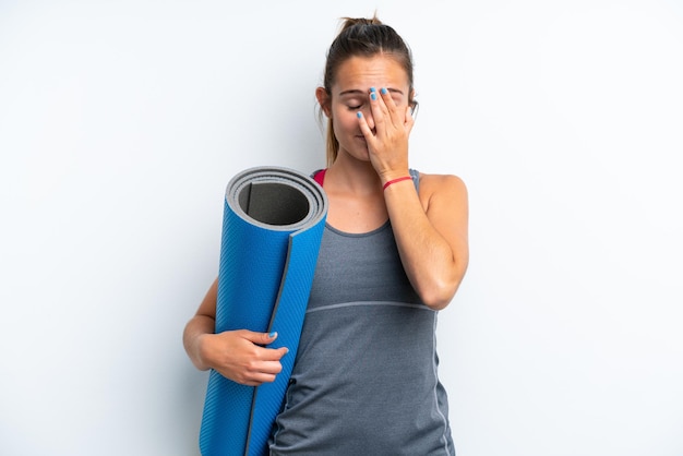 Young sport woman going to yoga classes while holding a mat isolated on white background with tired and sick expression