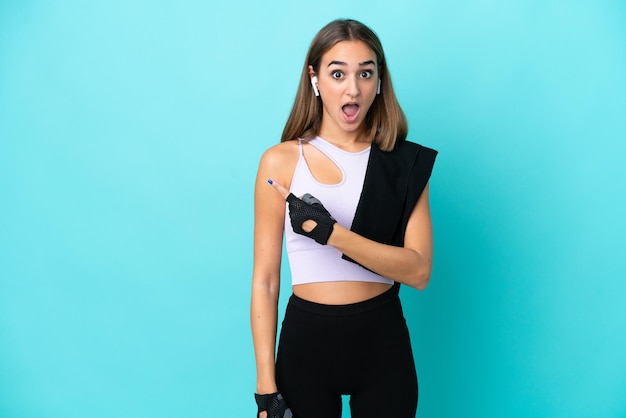 Young sport woman isolated on blue background surprised and pointing side