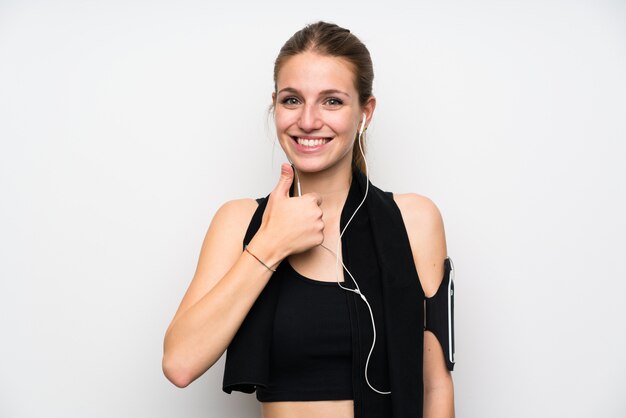 Young sport woman over isolated white wall giving a thumbs up gesture