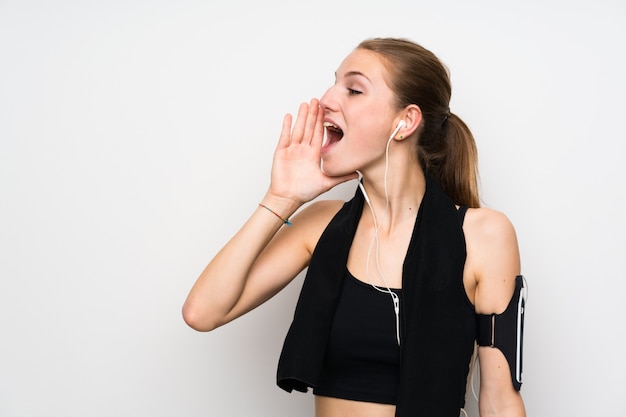 Young sport woman over isolated white wall shouting with mouth wide open