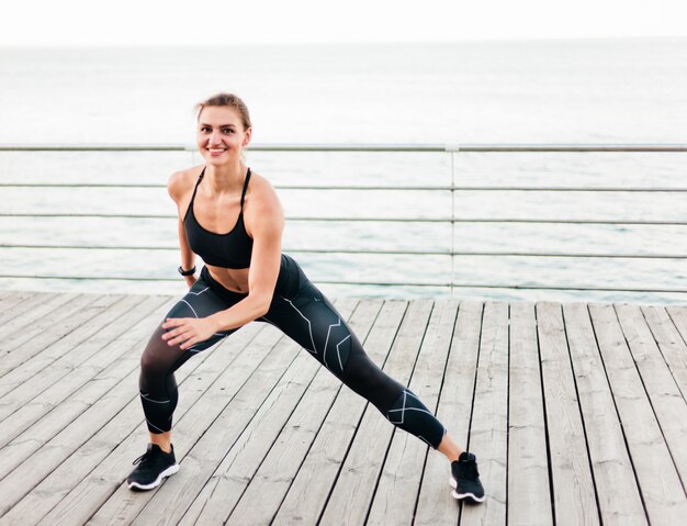 Young sport woman lunges on the beach terrace