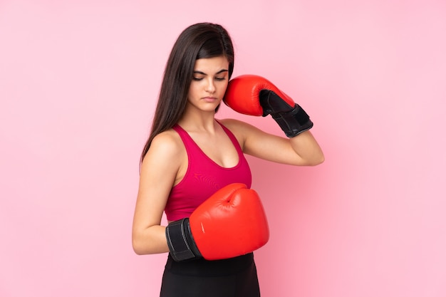 Young sport woman over pink wall with boxing gloves