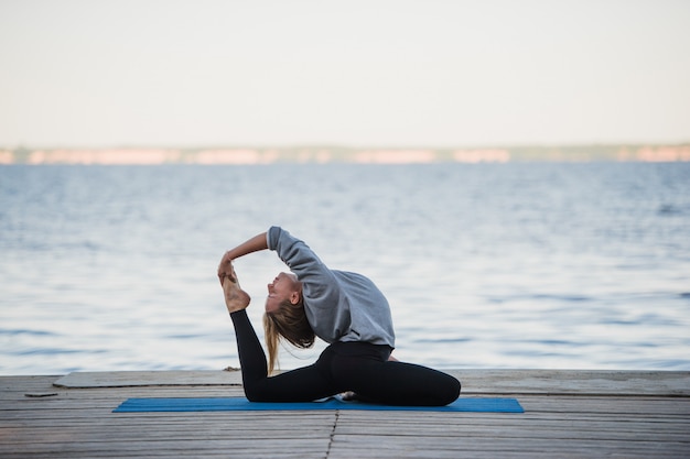 Young sport woman practicing yoga on the beach