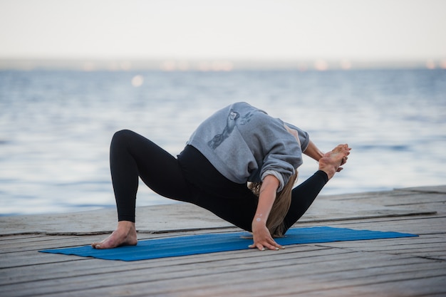 Young sport woman practicing yoga on the beach