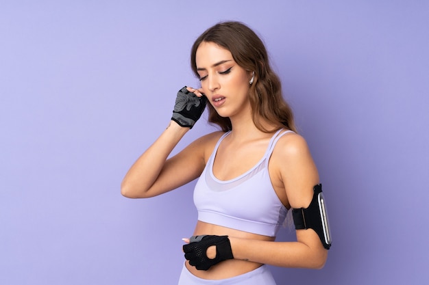 Young sport woman over purple wall listening music