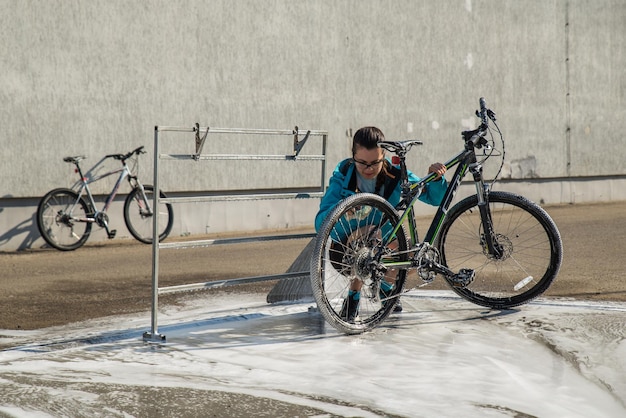 Young sport woman washing bicycle at selfservice car wash