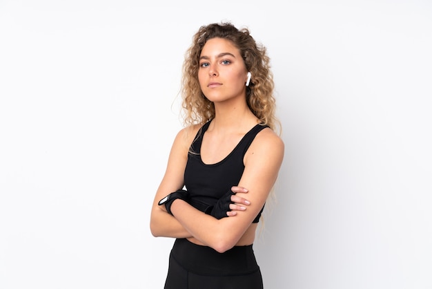 Young sport woman on white wall keeping the arms crossed