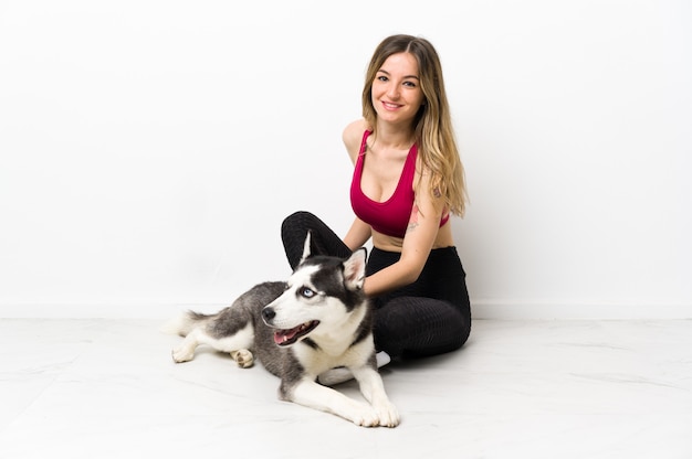 Young sport woman with her dog sitting on the floor