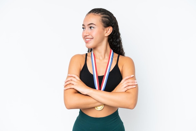 Young sport woman with medals isolated on white background with arms crossed and happy