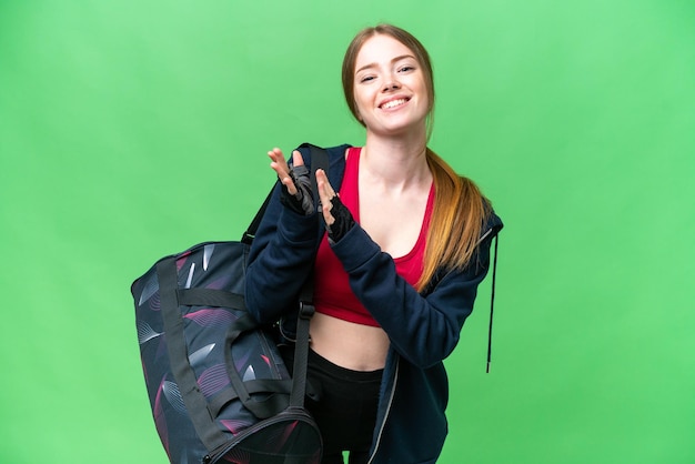 Young sport woman with sport bag over isolated chroma key background applauding after presentation in a conference