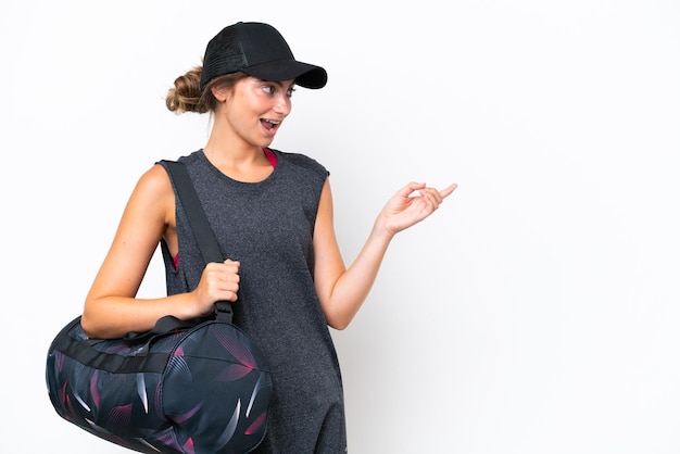 Young sport woman with sport bag isolated on white background pointing finger to the side and presenting a product