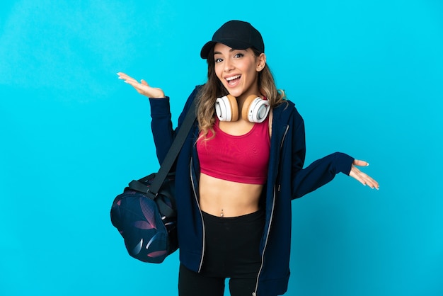 Young sport woman with sport bag posing isolated against the blank wall