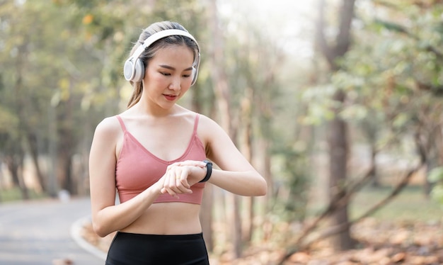 Young sport Woman with wireless headphone using smartwatch Checks Activity Tracker During Outdoor Exercise