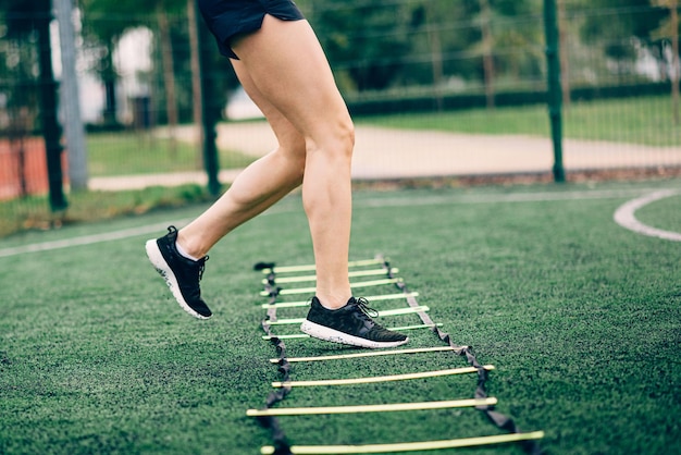 Young sportive woman trains with ladder drills  Cropped shot of legs