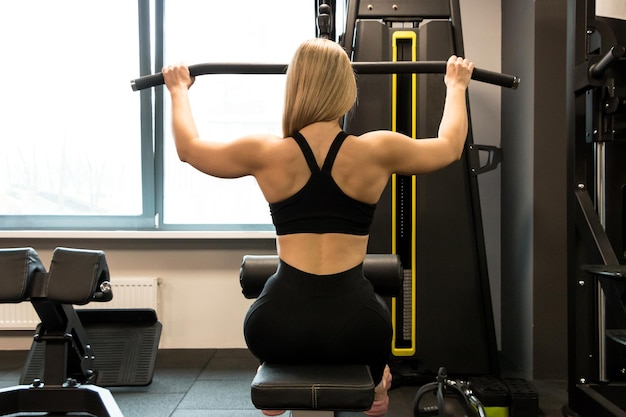 Young sports girl in sportswear does exercises in the gym