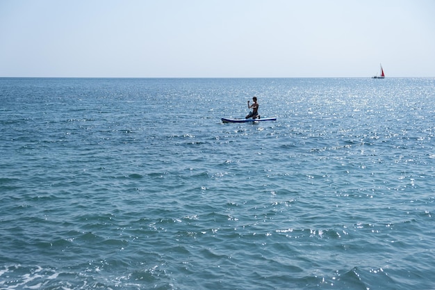 A young sports man with a child sails on a sup in the sea. Healthy lifestyle concept.