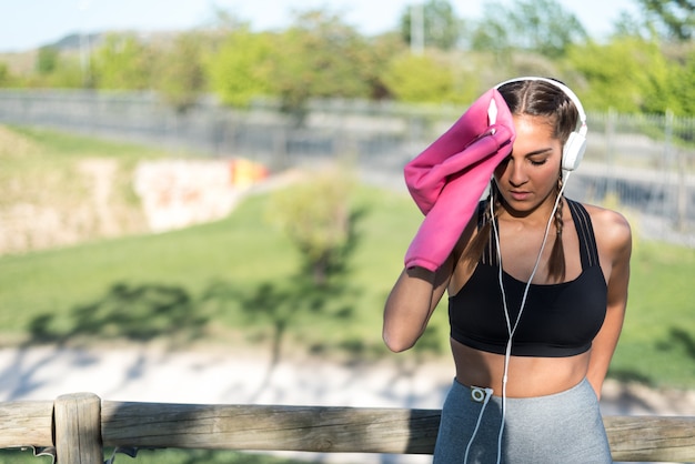 Photo young sports woman resting and wiping her sweat with a towel.