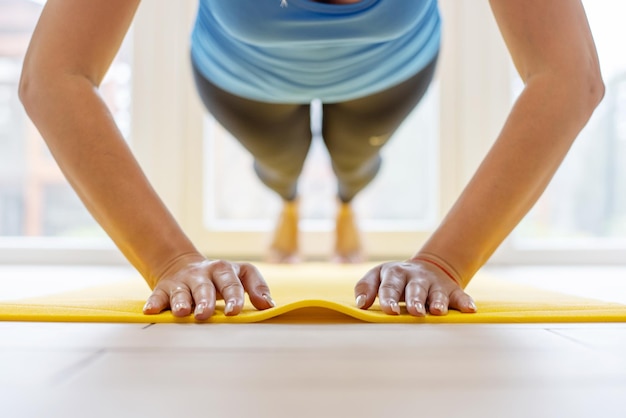 Young sports woman in sportswear on yoga mat doing push ups or pushing exercises