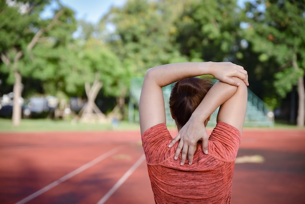 Young sports woman stretching on stadium track before running. 