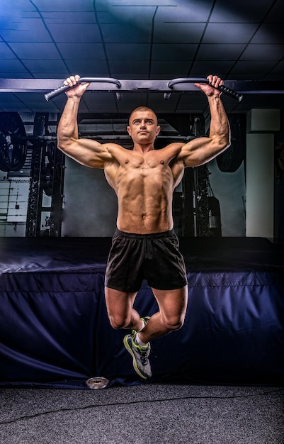 Young sportsman pulls up on a horizontal bar in a gym