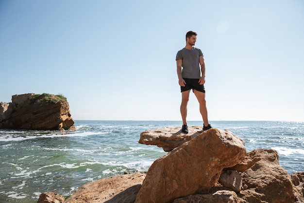 Young sportsman standing at the seashore on a rock