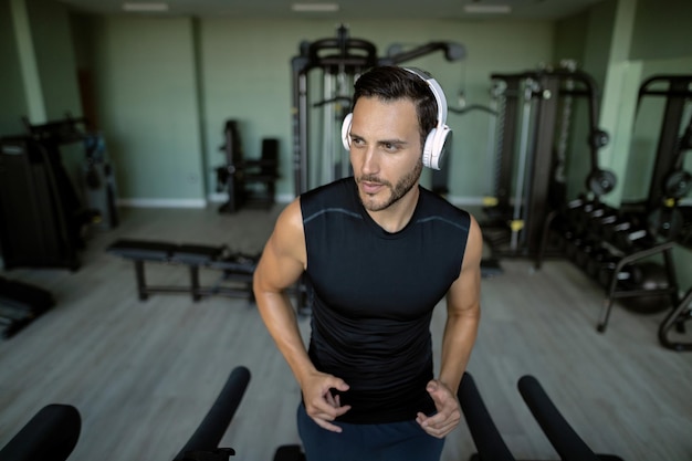 Young sportsman with headphones running on a treadmill in a gym