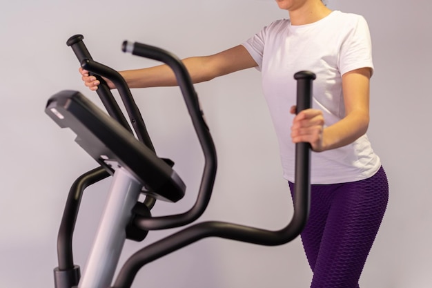 Young sportswoman exercising on elliptical cross trainer