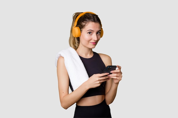 Young sportswoman listening to music motivated and focused holding phone