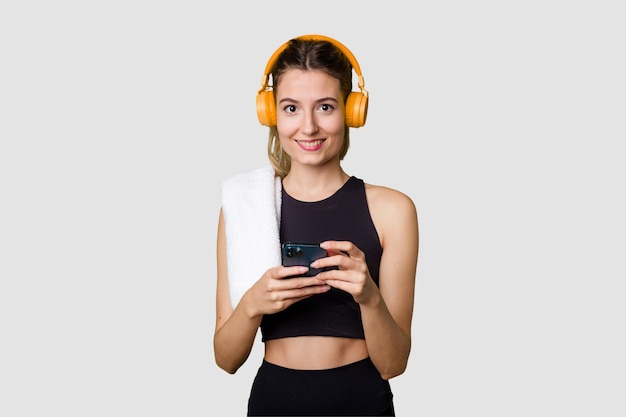 Young sportswoman listening to music motivated and focused holding phone