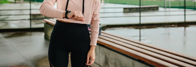 Young sportswoman looking activity bracelet outdoors